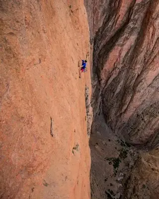 a person is rappelling down a rock wall at gîte taghia ahansal in Taghia
