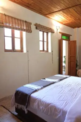a bedroom with a large bed in a room with windows at Dar Fes Zahra in Fès