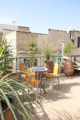 a table and chairs on a balcony with plants at Dar Fes Zahra in Fès
