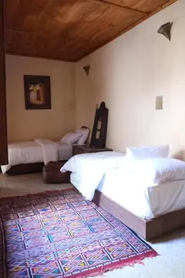 a bedroom with three beds and a rug on the floor at Dar Fes Zahra in Fès