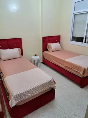 two beds sitting in a room with a window at Appartement Atlas City Center 2 in Fès