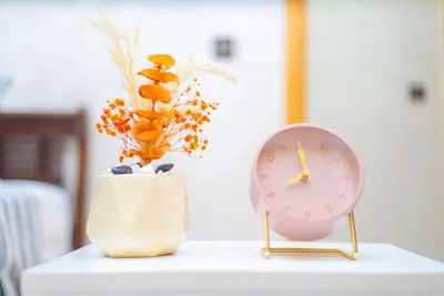 a clock and a vase with flowers on a table at Familiale, raffinement et calme, entourée d'une vue sur le jardin - À proximité de l'aéroport et de Marjane in Fès