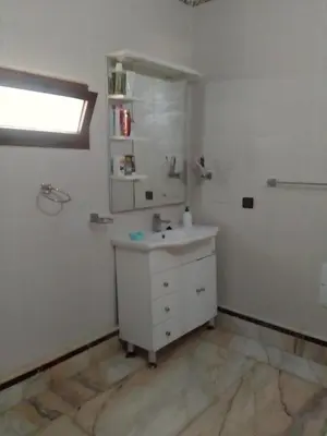 a white bathroom with a sink and a mirror at Tifelt in Tiflet
