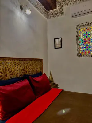 a bedroom with a bed with red pillows and a window at Appartement khmissa in Fès al Bali