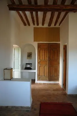 a room with a large wooden door and a kitchen at Dar Tasmayoun in Aït Ourir