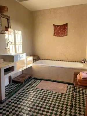a bathroom with a tub and a checkered floor at Dar Tasmayoun in Aït Ourir