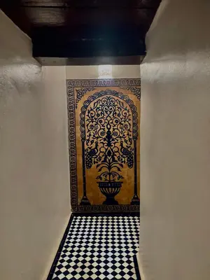 a hallway with a tile floor and a stenciled wall at Dar Tagore in Fès