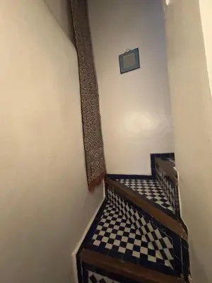 a hallway with a stairway with a checkered floor at Dar Tagore in Fès