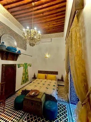 a bedroom with a bed in a room with a chandelier at Riad Phœnix in Fès al Bali