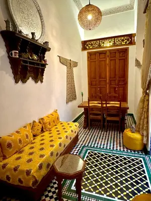a living room with a yellow couch and a table at Riad Phœnix in Fès al Bali