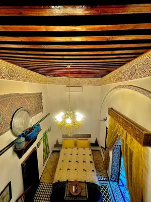 a dining room with a table and a chandelier at Riad Phœnix in Fès al Bali
