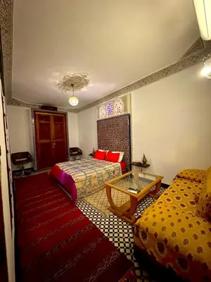 a bedroom with two beds and a table and a couch at Riad Phœnix in Fès al Bali