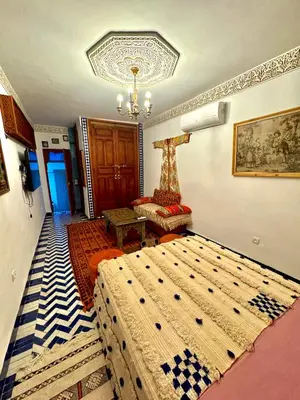 a bedroom with two beds and a chandelier at Riad Phœnix in Fès al Bali