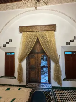 a bedroom with a bed and a wooden door at Riad Phœnix in Fès al Bali