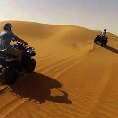 two people riding on motorcycles in the desert at Aaladdin luxury camp in Merzouga