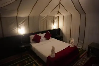 a bedroom with a canopy bed with red and white pillows at Aaladdin luxury camp in Merzouga