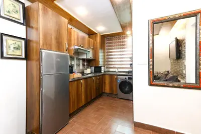 a kitchen with wooden cabinets and a stainless steel refrigerator at Dar Ibn Majdoub Prive Entier in Fès