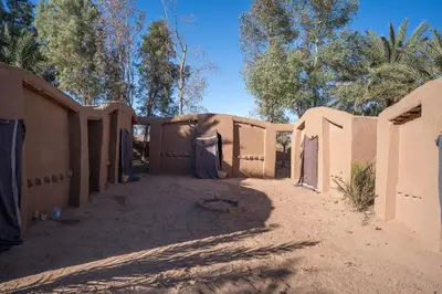 a building in the desert with trees in the background at Oasis source de vie in Mhamid