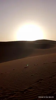 a sunset in the desert with the sun setting at Oasis source de vie in Mhamid