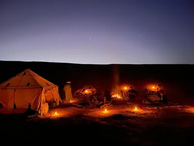 a group of people sitting around a tent at night at Oasis source de vie in Mhamid
