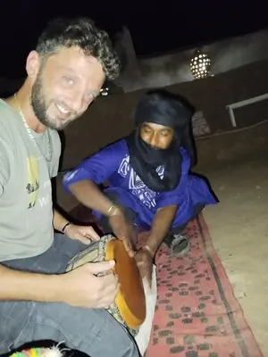 a man sitting next to a woman holding a hot dog at Oasis source de vie in Mhamid