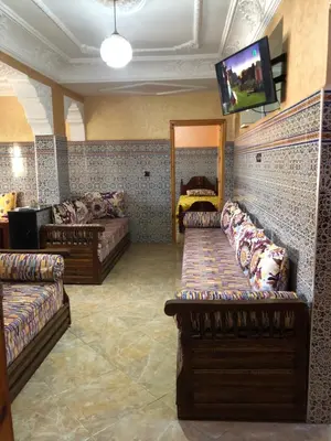 a living room with couches and a tv on a wall at Mahmoud moulay Yacoub 1 in Moulay Yacoub