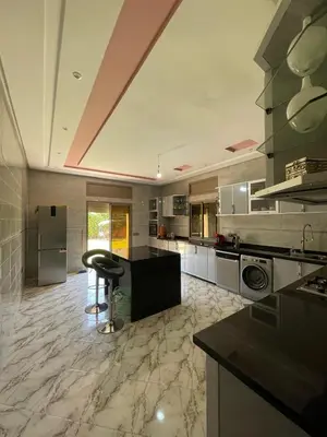 a large kitchen with a counter and a bar stool at Villas Près De Chez Vous in Amezrou