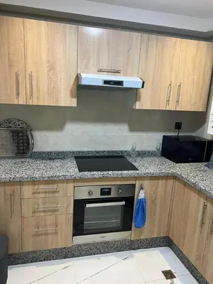 a kitchen with wooden cabinets and a stove top oven at Appartement la Cañada in Ville Nouvelle