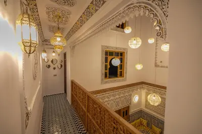 a hallway of a building with a staircase and chandeliers at Dar Golden Ziat in Fès