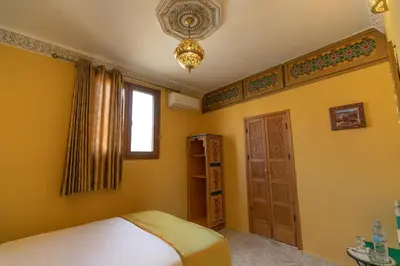 a bedroom with a bed and a window and a chandelier at Dar Golden Ziat in Fès