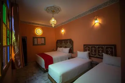 two beds in a room with orange walls at Dar Golden Ziat in Fès