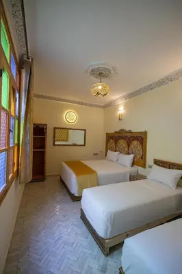 a hotel room with two beds and a chandelier at Dar Golden Ziat in Fès