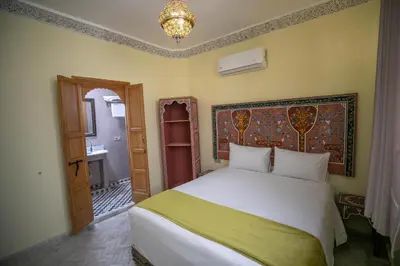 a bedroom with a white bed and a bathroom at Dar Golden Ziat in Fès