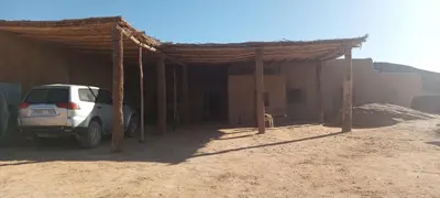 a car parked in front of a building in the desert at Segaoui House in Merzane