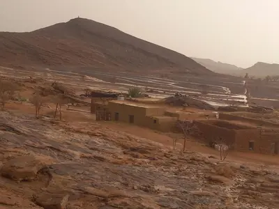 a village in the desert with a mountain in the background at Segaoui House in Merzane