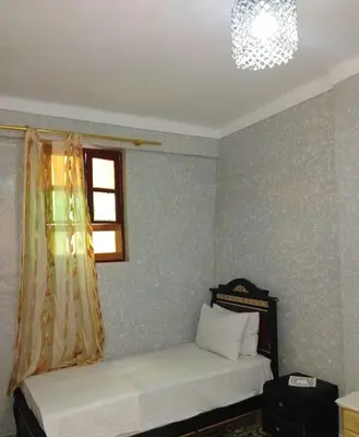 a bedroom with a bed and a window and a chandelier at Appartement lala Houriya fez in Fès