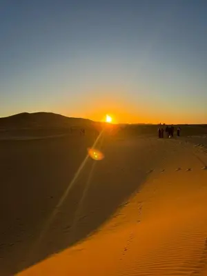a group of people walking in the desert at sunset at Luxury Camp Glamping in Merzouga