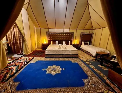 a bedroom with a bed and a blue rug in a tent at Luxury Camp Glamping in Merzouga
