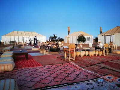 a patio with white tents and tables and chairs at Luxury Camp Glamping in Merzouga