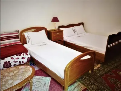 a bedroom with two beds and a chair and a table at Chambres d'Hôtes Hayat in Dar Mahres