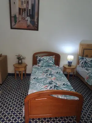 a bedroom with a wooden bed and two tables at Chambres d'Hôtes Hayat in Dar Mahres