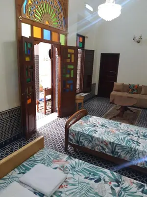 a room with a bed and a couch and a window at Chambres d'Hôtes Hayat in Dar Mahres