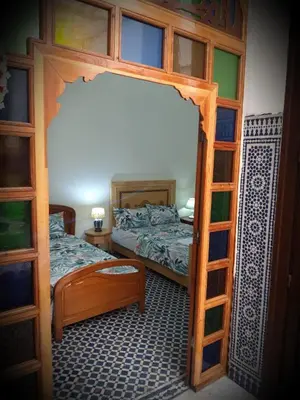 a bedroom with two beds and a wooden bunk bed at Chambres d'Hôtes Hayat in Dar Mahres