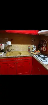 a red kitchen with a sink and a stove at Nice appartement au centre de IFRANE in Ifrane