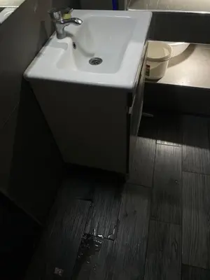 a bathroom with a white sink and a wooden floor at Logement bien placé in Meknès
