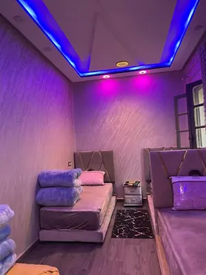 a room with purple lights and two beds in it at Logement bien placé in Meknès