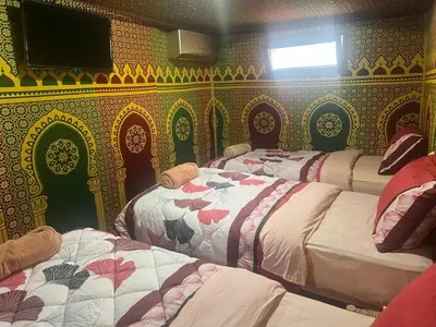 a room with three beds and a tv on a wall at Villa Maroua in Madkhal Meski