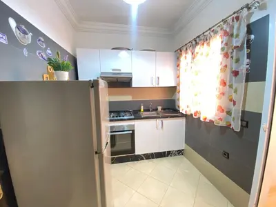 a small kitchen with white cabinets and a refrigerator at Mahdi Oussama in Tazelaft