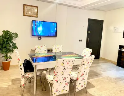 a dining room table with chairs and a tv on the wall at Mahdi Oussama in Tazelaft