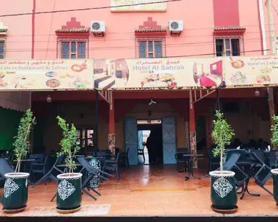 a building with chairs and plants in front of it at Hotel Sahara in Tafrourht nʼAït Bou Jijou